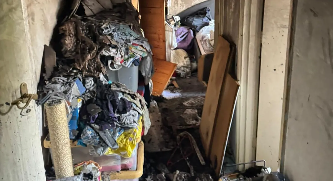 Gang na een brand vol kleding en spullen onder het roet, tegen beroete wanden