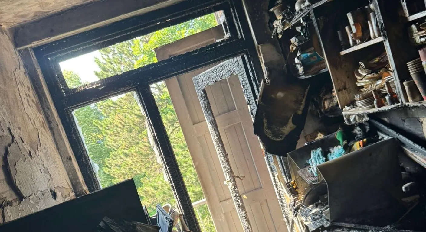 Keuken na een brand met verkoolde kastjes en planken en een zwartgeblakerd raamkozijn