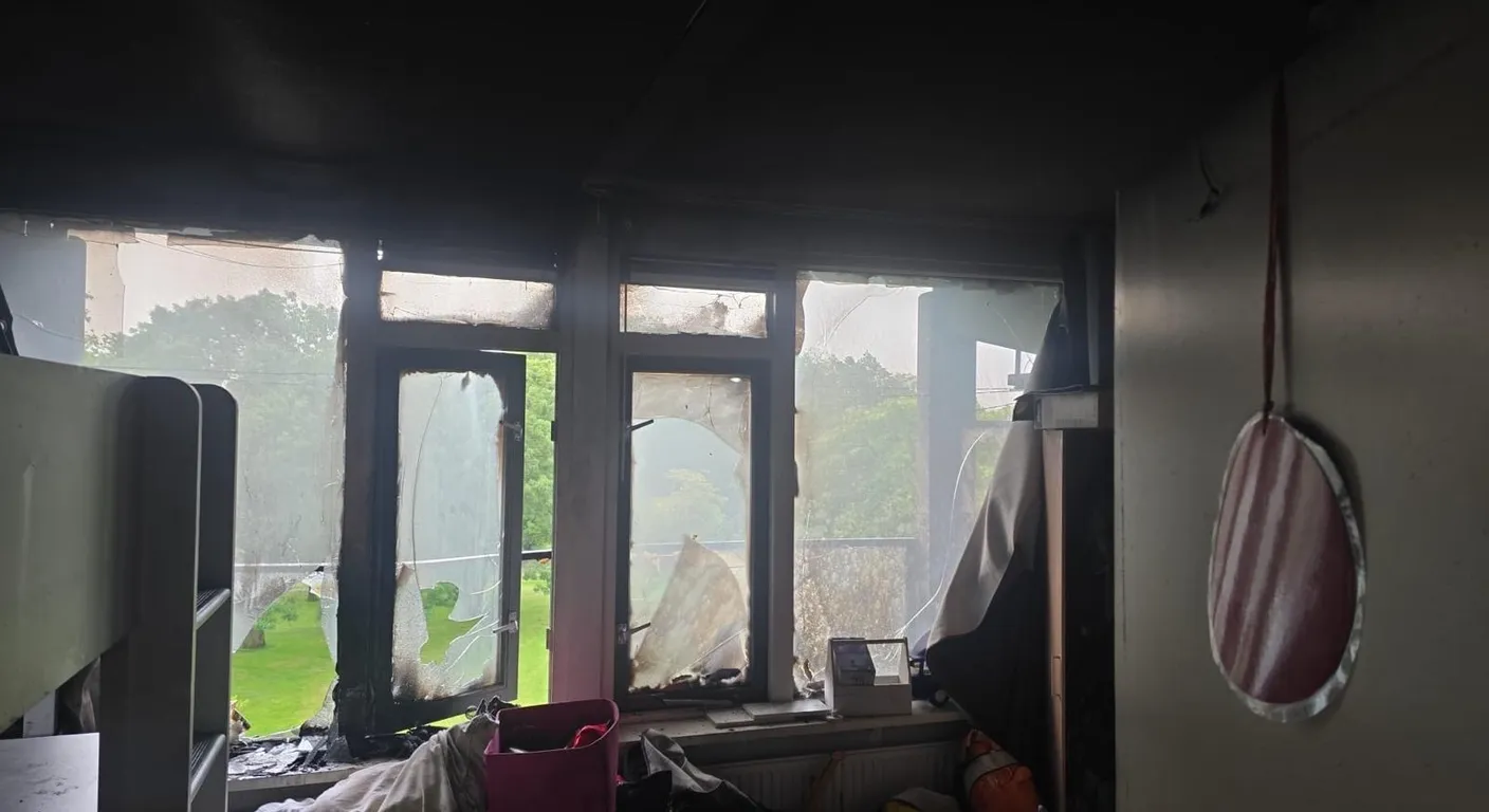 Kamer na een brand met rookzwarte wanden en plafond en door de hitte vervormde ramen