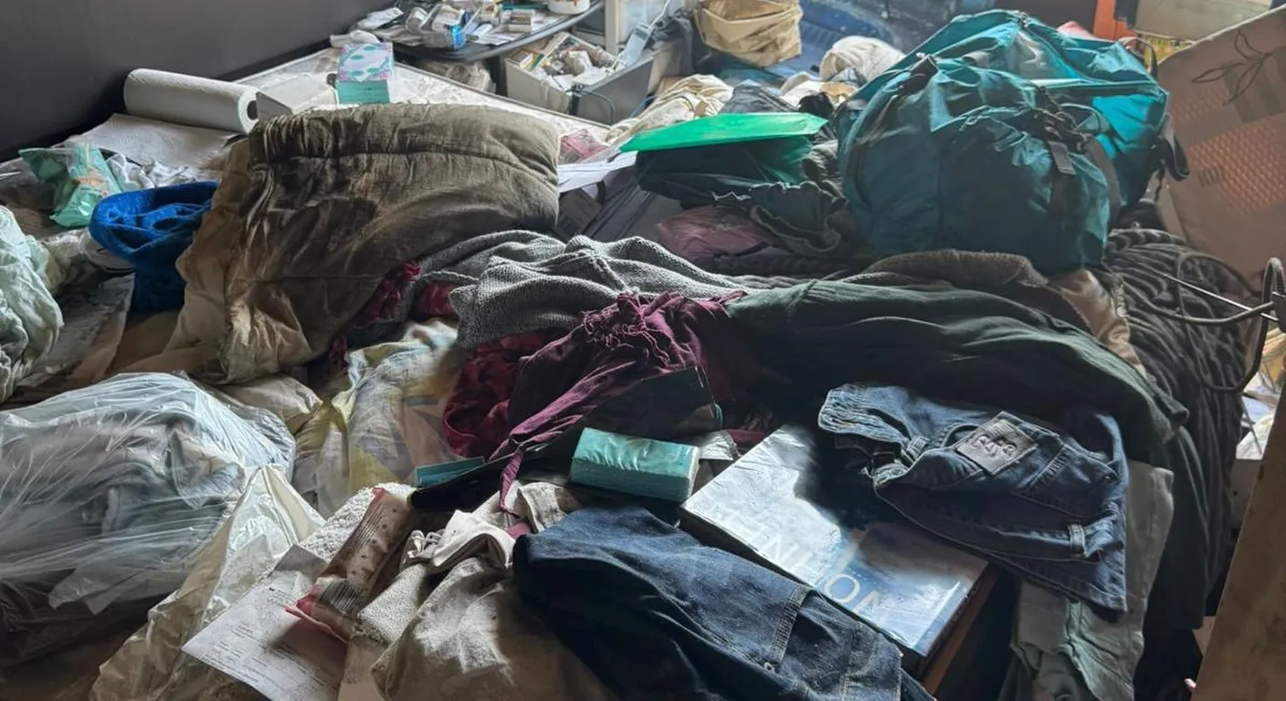 Slaapkamer na een brand met kleding, tassen en papieren die onder het roet liggen