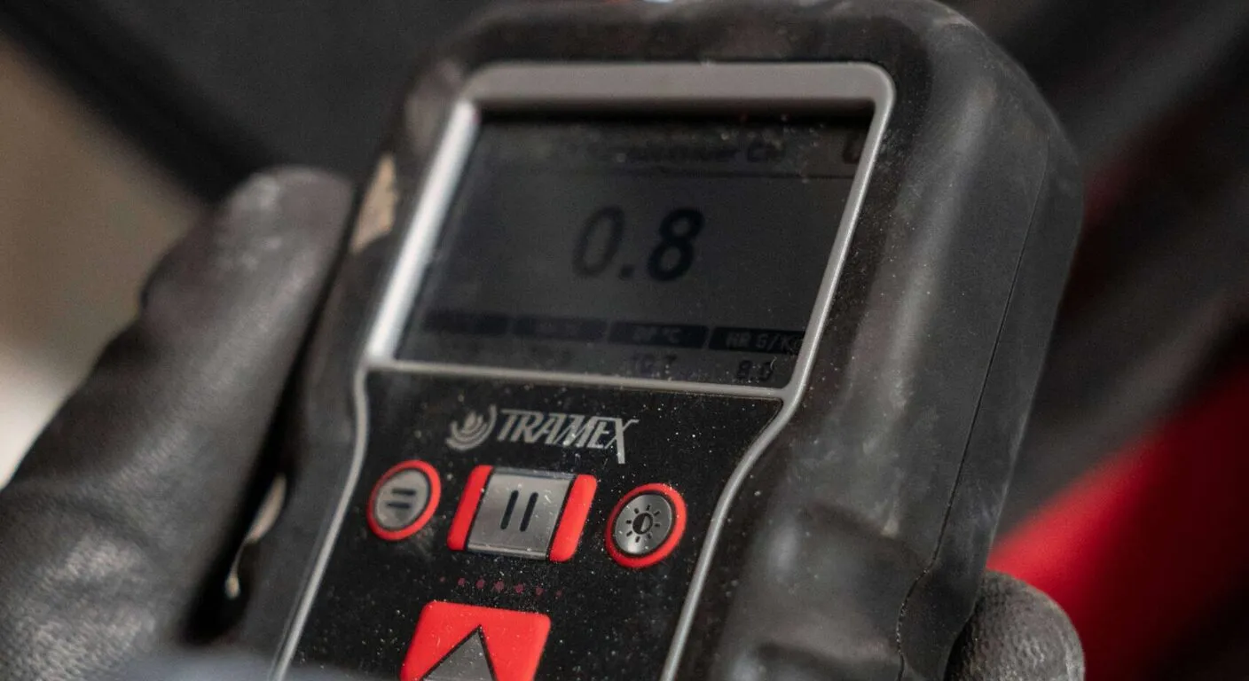 Vochtmeter in een gehandschoende hand toont een meetwaarde