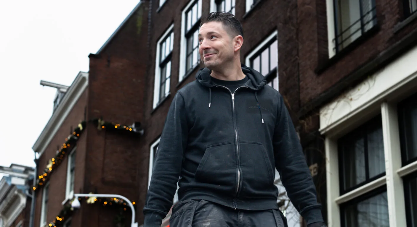 Specialist van Fizzee Groep onderweg naar een schadelocatie in een Amsterdamse straat